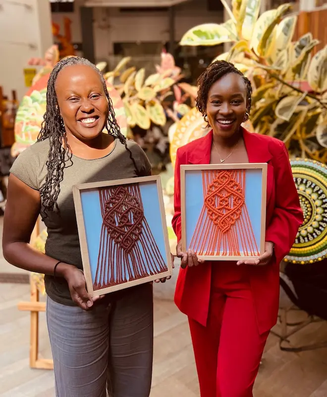 Two Osona Yarns crafters holding their framed macramé pieces